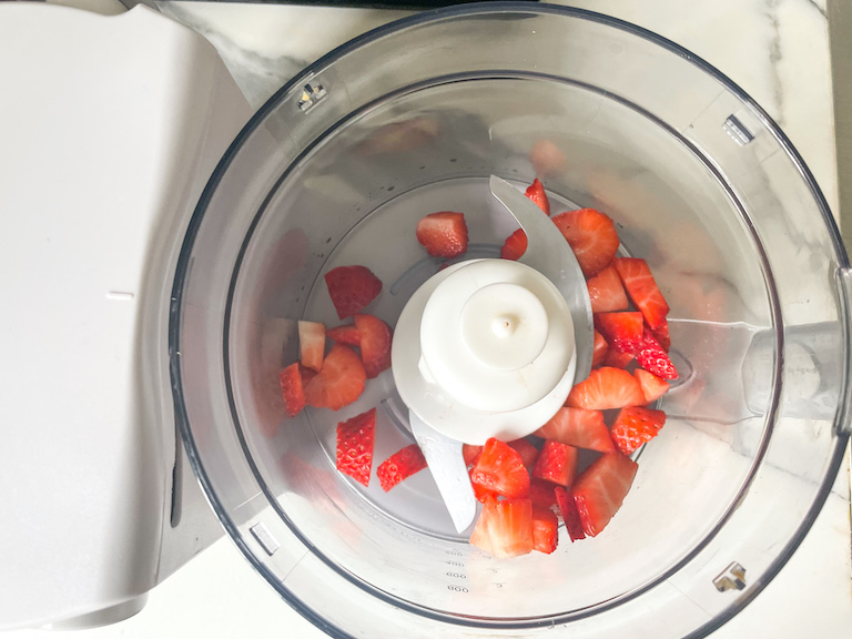 Chopped strawberries in the bowl of a food processor