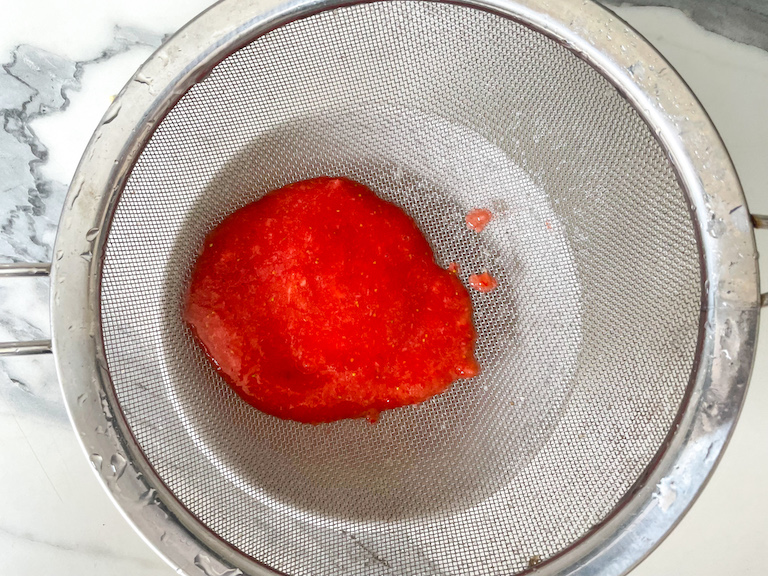 Strawberry purée in a fine mesh strainer