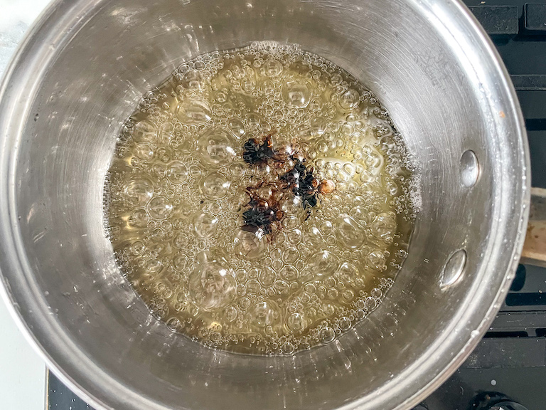 Root beer flavoring dropped in a pan of boiling sugar