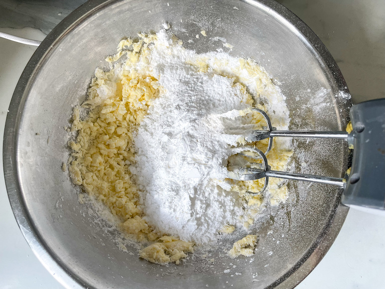 Powdered sugar and butter in a bowl with a mixer
