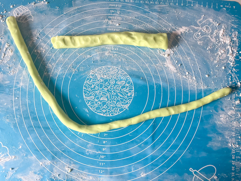 Ropes of green butter mint dough on a rolling mat