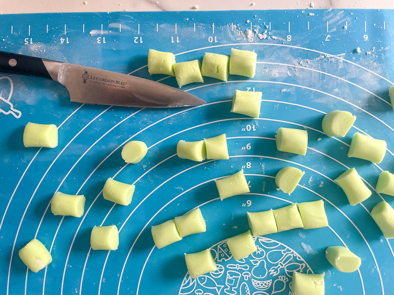 A knife and homemade green butter mints on a silicone mat