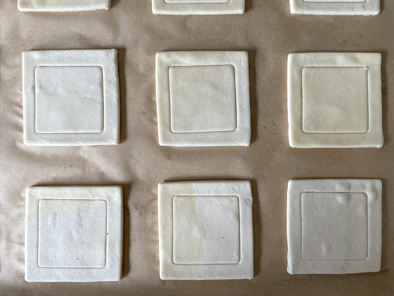 Puff pastry squares on a sheet of parchment