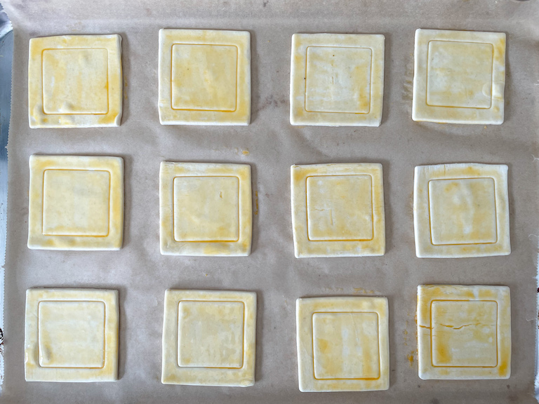 Squares of egg washed pastry on a tray