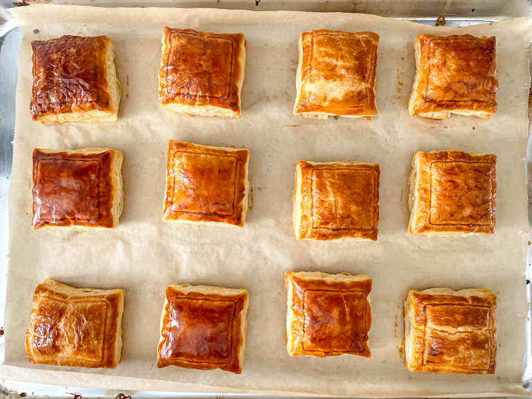 Golden brown puff pastry squares on a tray
