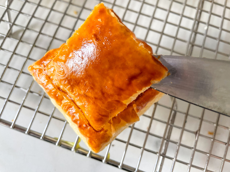 Knife lifting a square of baked puff pastry