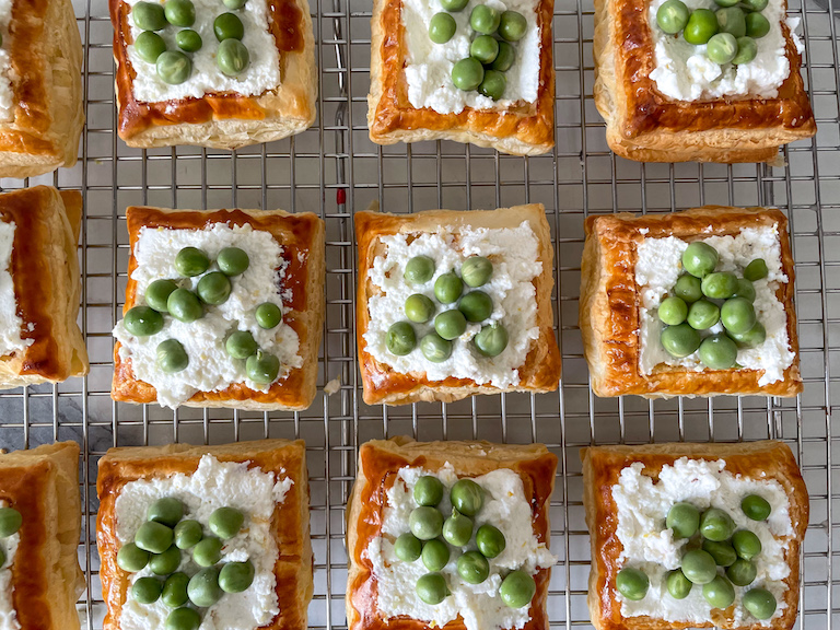 Peas arranged on top of ricotta cheese on squares of pastry