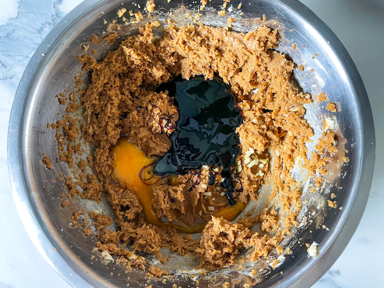 Black treacle and egg added to ingredients in a metal bowl