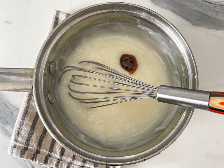 Adding yellow food coloring and vanilla bean paste to homemade vanilla pudding