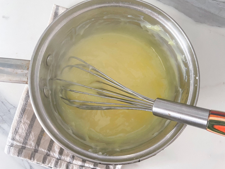 Homemade vanilla pudding in a saucepan with a whisk 