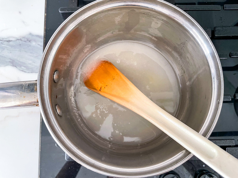 Caramel sauce ingredients in a saucepan with a spoon