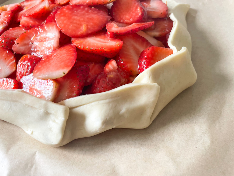 The folded edges of a strawberry galette, before baking