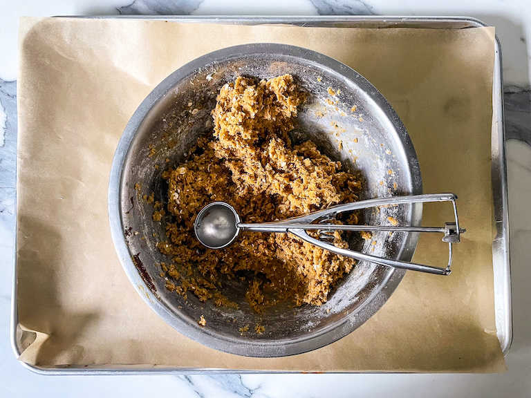 A bowl of cookie dough and a scoop arranged on a tray
