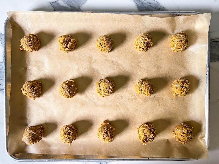 Scoops of cookie dough on a parchment lined tray