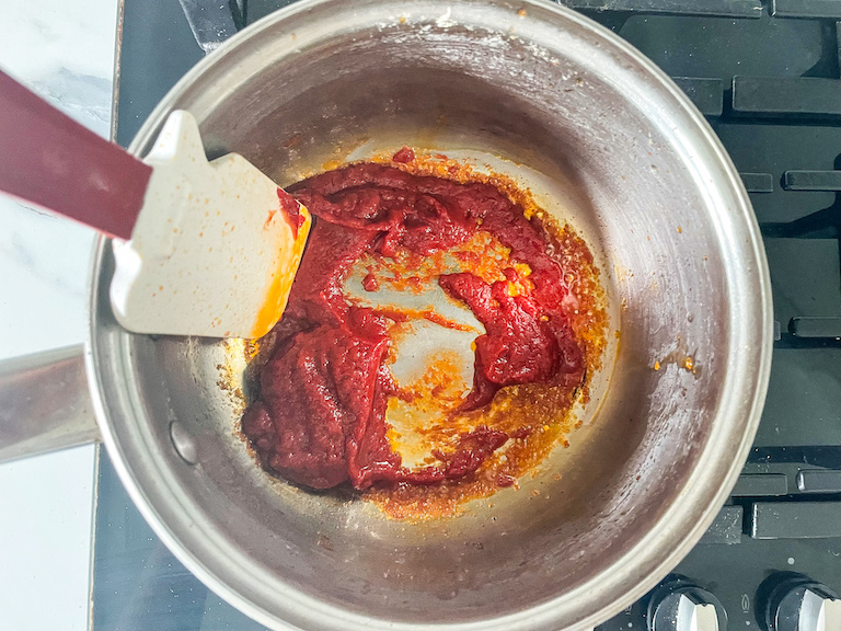 Rubber spatula in a saucepan with tomato paste and oil