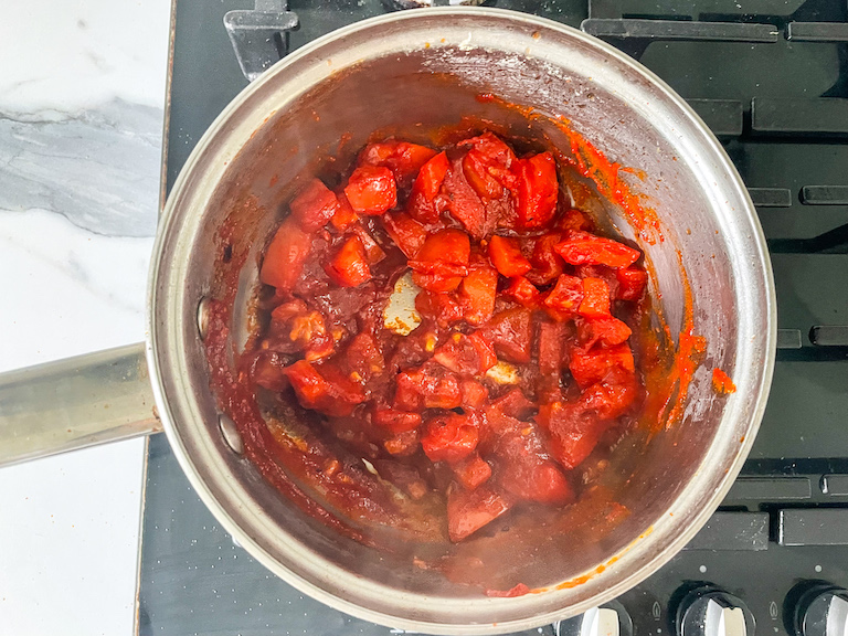 Metal saucepan with tomatoes, on stovetop