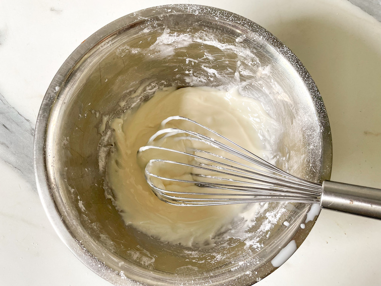 Icing ingredients in a bowl with a whisk