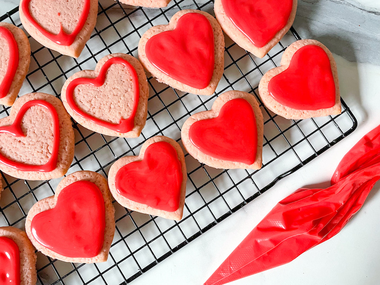 Heart shaped cookies with red icing on a wire rack
