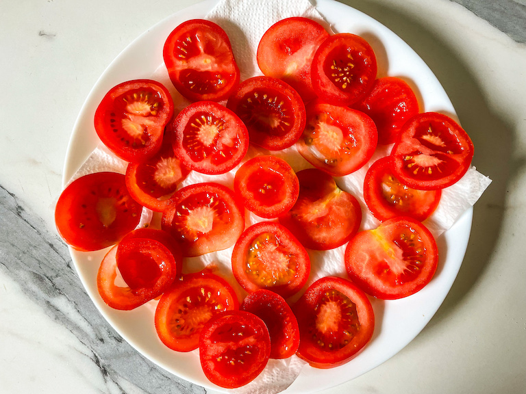 Red tomato slices on a white plate