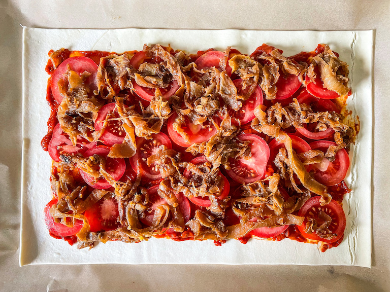 Caramelised onions and tomatoes arranged on a rectangle of puff pastry