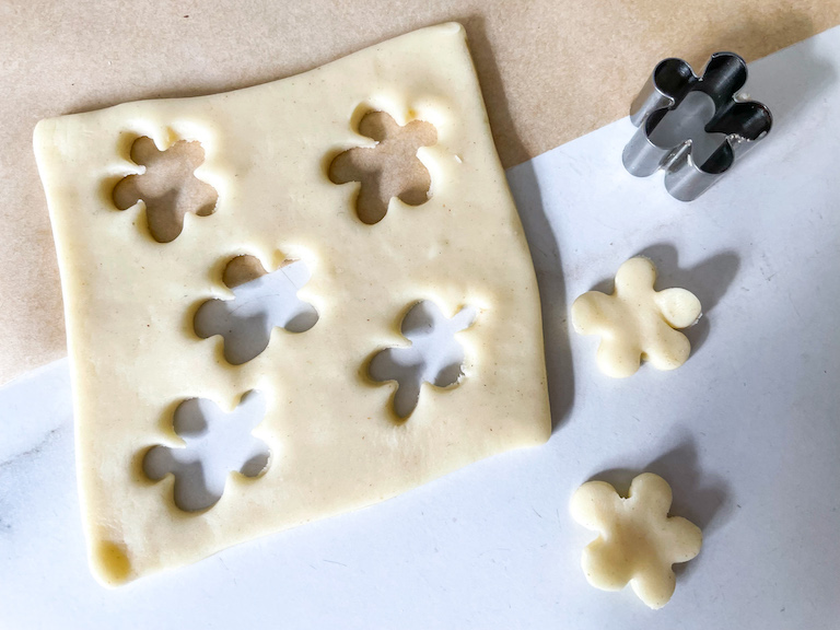 A square of pastry, cutter, and flower shapes