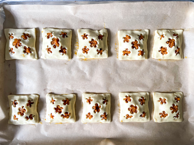 Unbaked pumpkin hand pies arranged on a sheet of parchment