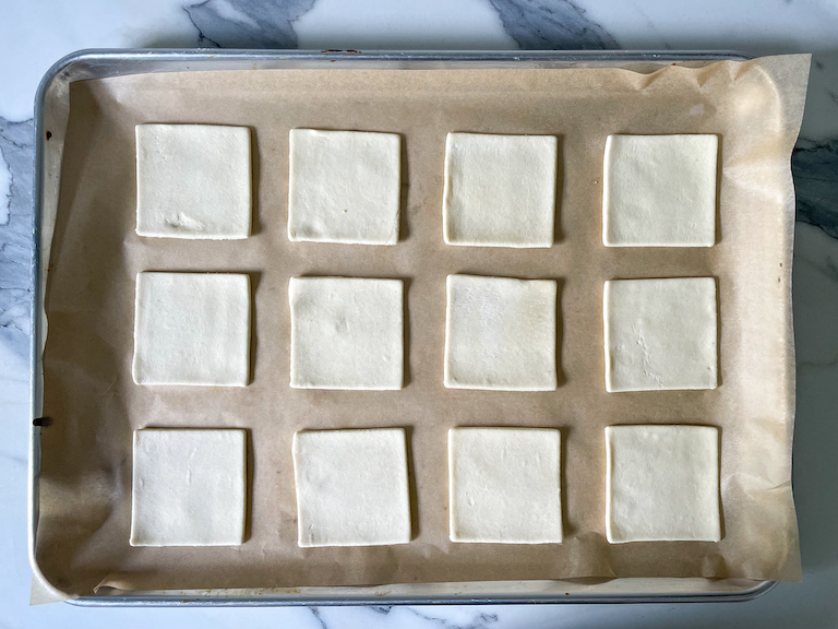 Squares of puff pastry on a parchment lined tray