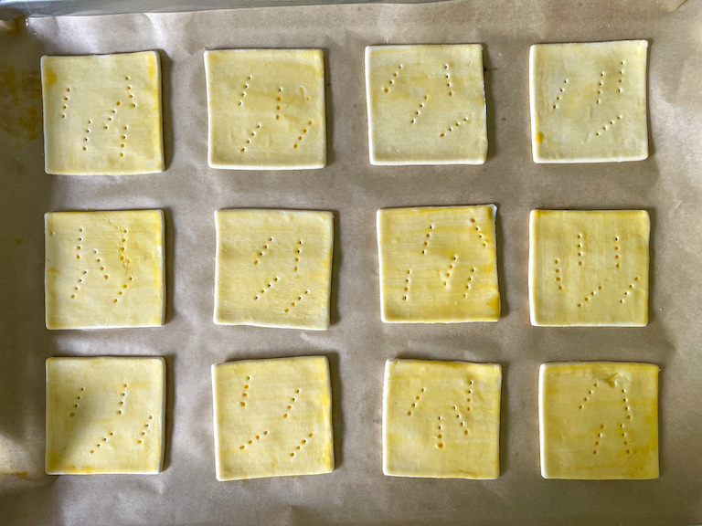 Egg washed squares of puff pastry on a tray