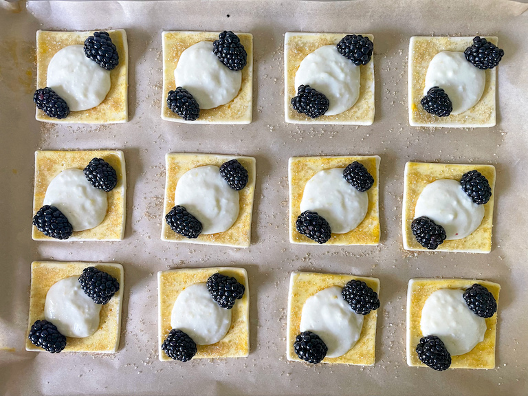 Unbaked puff pastry squares with cheese filling and fresh berries