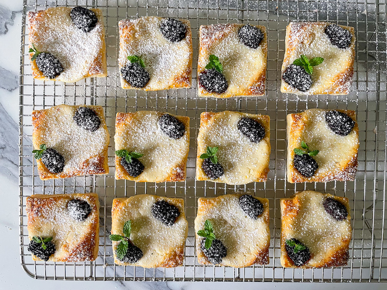Blackberry cheese pastries dusted with sugar, on a wire rack