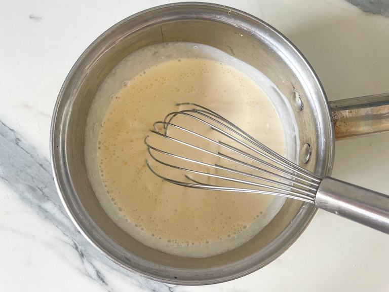 Cream and sugar in saucepan with a whisk