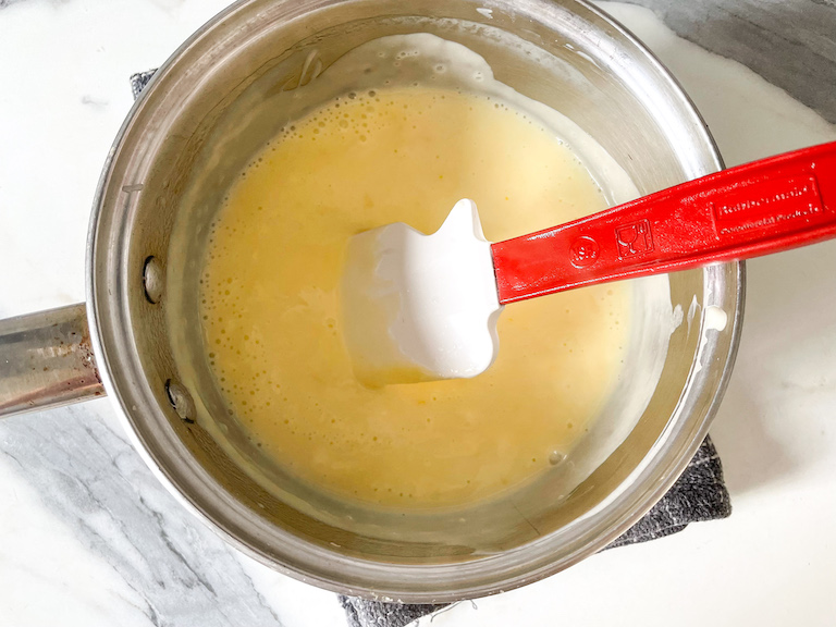 Lemon posset mixture in saucepan with spatula