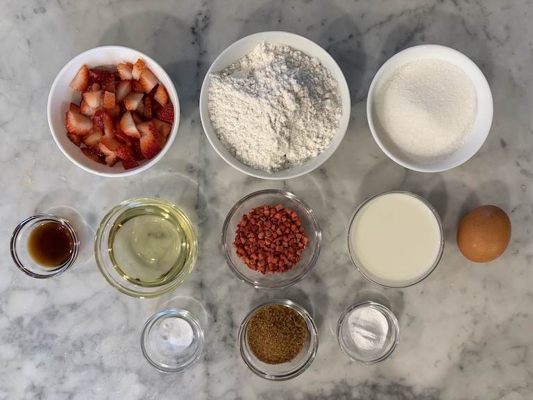 Strawberry muffin ingredients arranged on a marble surface