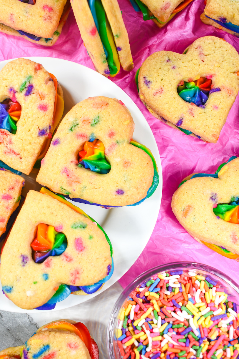 A plate of heart shaped cookies with rainbow buttercream