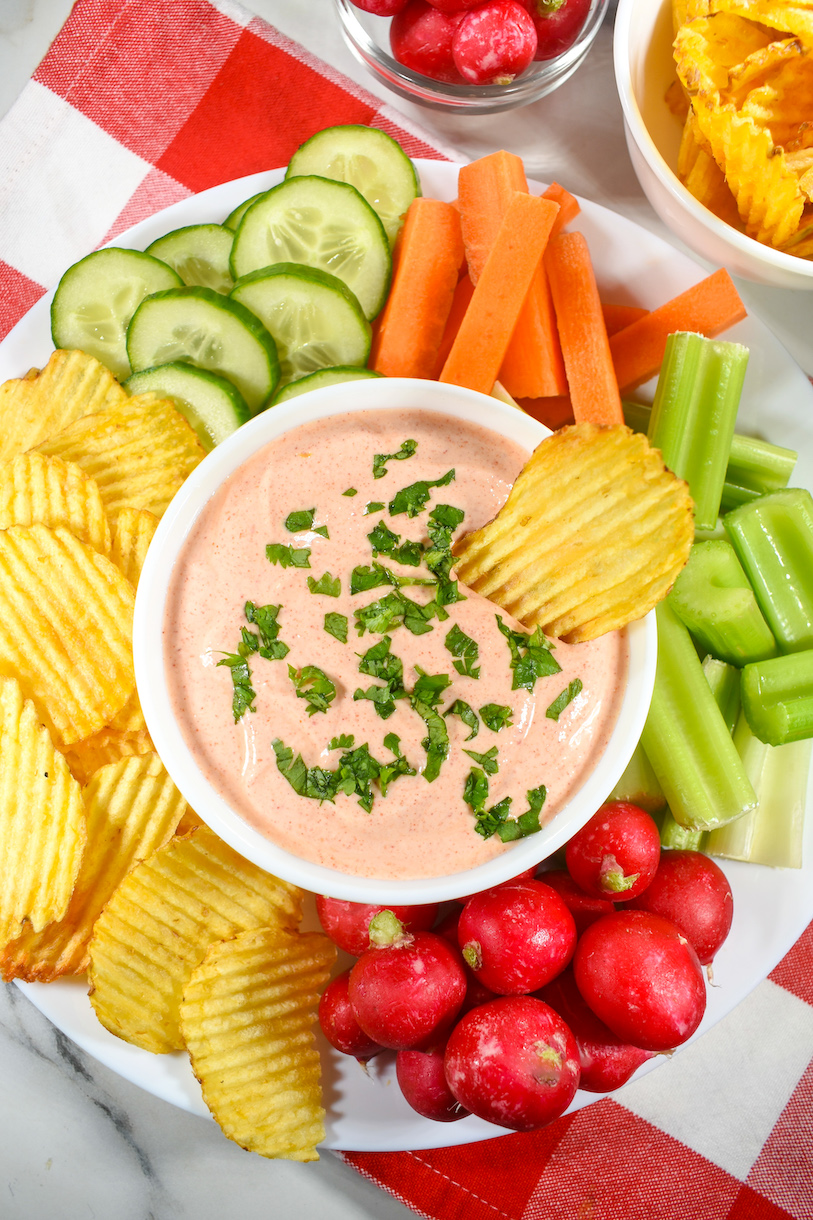 a bowl of dip surrounded by chips and vegetables