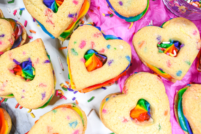Heart shaped rainbow cookies on a sheet of pink tissue