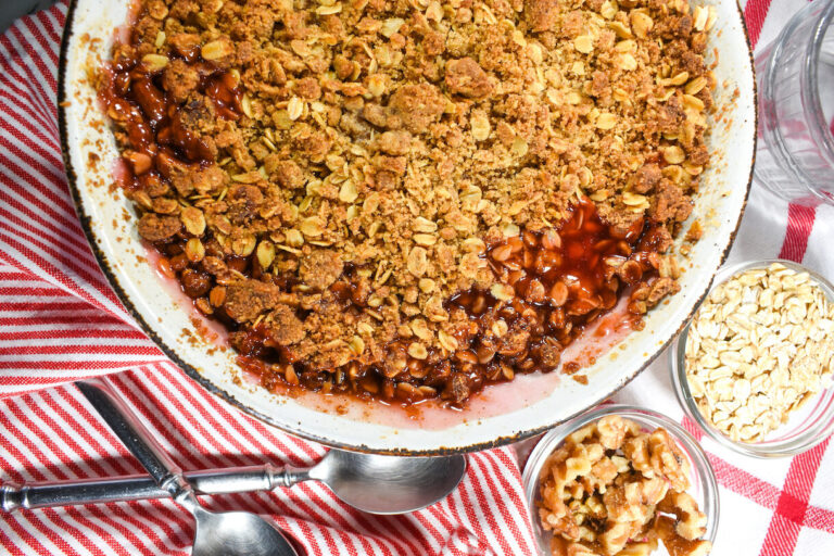 Strawberry and rhubarb cobbler, a dish of walnuts, a dish of oats, and red striped tea towels