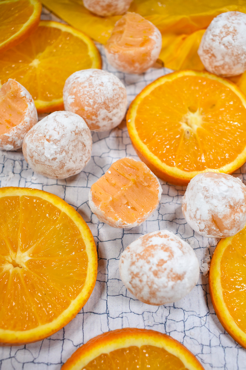 Creamsicle truffles and sliced oranges on a textured surface