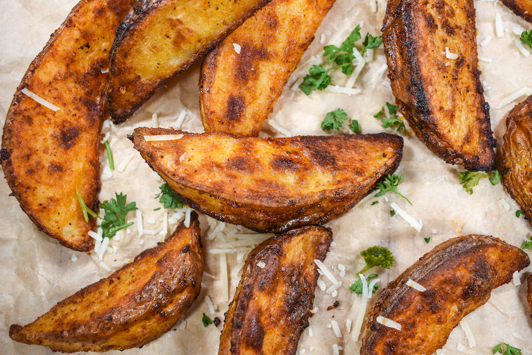 Roasted potato wedges garnished with cheese and herbs