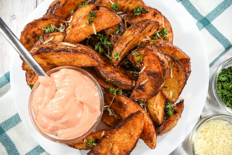 A plate of oven roasted potatoes with sriracha dipping sauce
