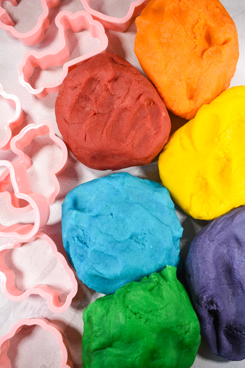 Balls of playdough and cookie cutters on a white surface