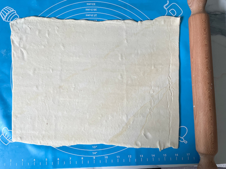 puff pastry on a rolling mat with rolling pin
