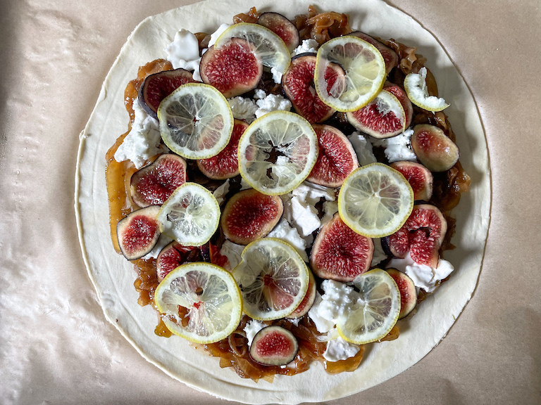 Figs and lemons arranged on unbaked puff pastry