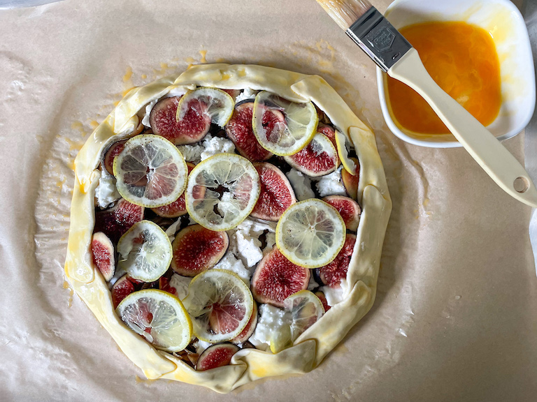 Dish of egg wash, brush, and unbaked fig and goat cheese puff pastry tart