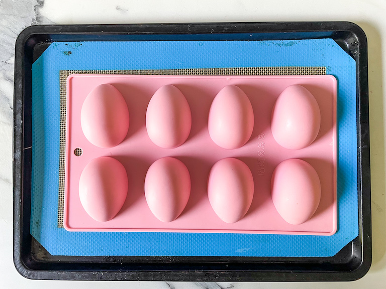 A pink egg mould upside down on a tray