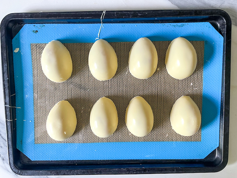 White chocolate eggs arranged in rows on a tray