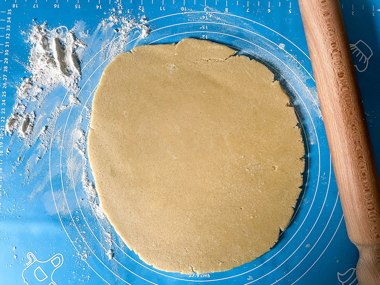 Cookie dough on a rolling mat with rolling pin