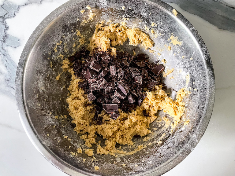 Cookie dough ingredients in a bowl with chopped chocolate