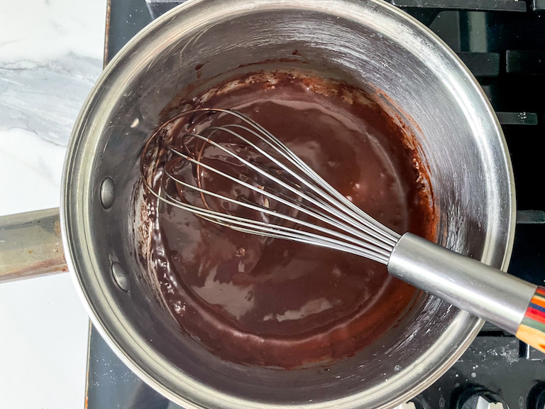 Chocolate frosting in a pan with a whisk