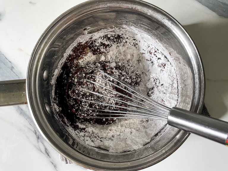Whisk, chocolate, and confectioner's sugar in a saucepan